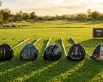 Lineup of modern flagship golf drivers resting on tournament tee turf during sunset